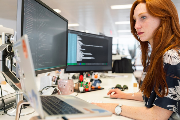 A woman in an office researching the proposal management process on her computer